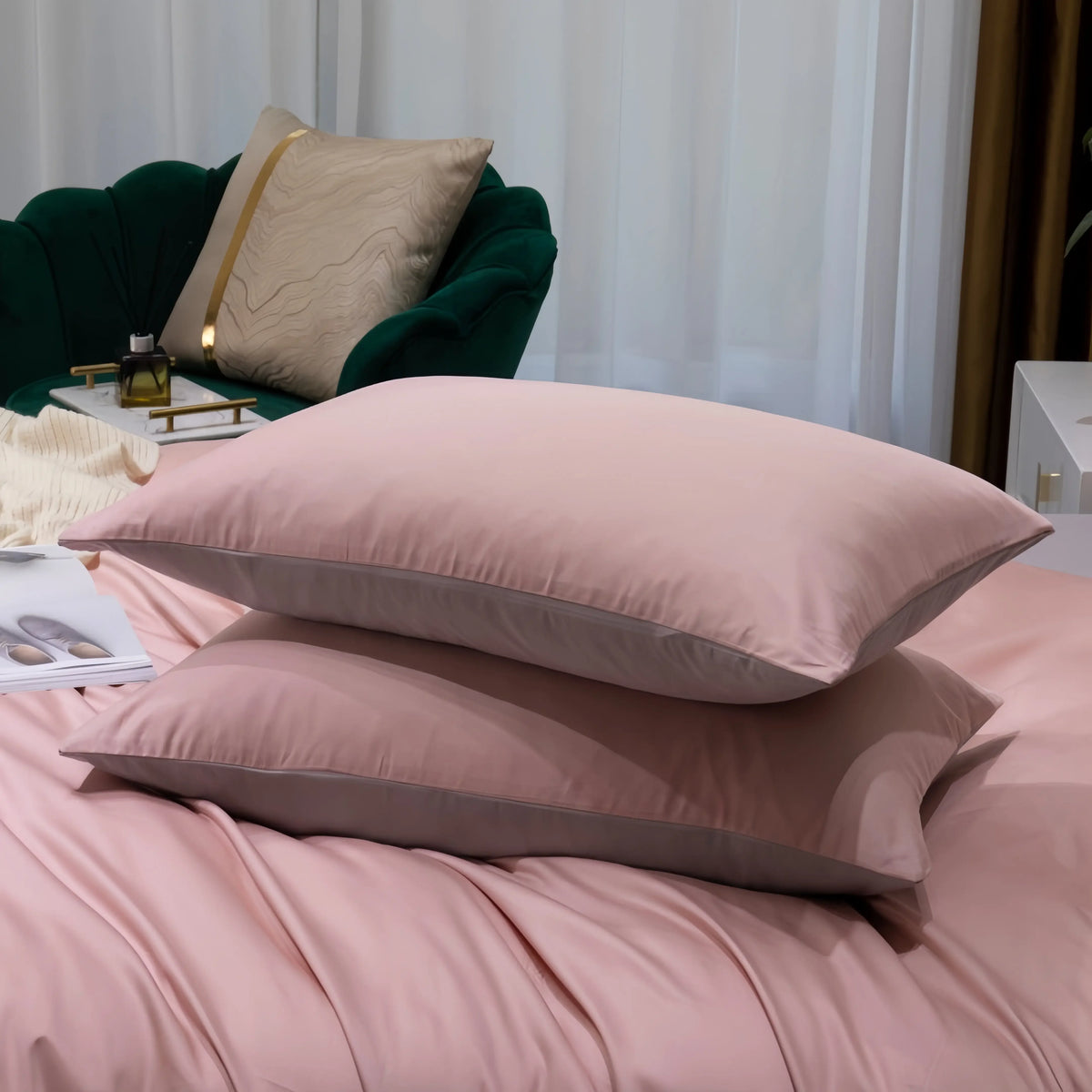 Soft pink cotton pillowcases on a cozy bed with elegant green armchair in background